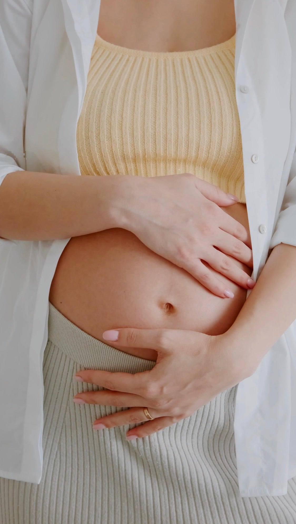 pregnant woman in yellow shirt holding her pregnant stomach